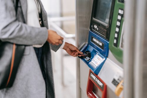 Free Side view of crop unrecognizable female in stylish clothes using credit card while buying metro ticket via electronic machine Stock Photo