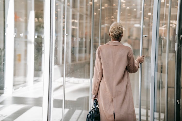 Unrecognizable Trendy Black Woman Opening Glass Door In Modern Workspace