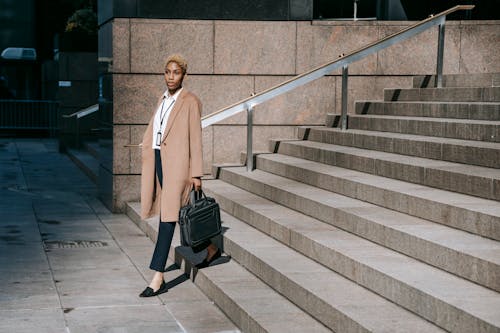 Free Confident young black female employee walking downstairs of contemporary building Stock Photo