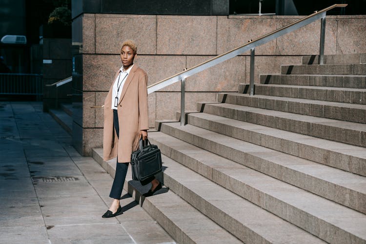 Confident Young Black Female Employee Walking Downstairs Of Contemporary Building