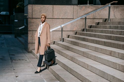 Free Stylish young African American businesswoman with short blond hair in elegant outfit walking downstairs of modern building after workday Stock Photo