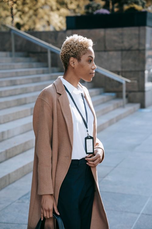 Free Side view of concentrated young black female manager with short blond hair in classy outfit standing on street and waiting for meeting Stock Photo