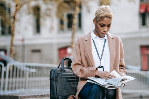 Free Concentrated ethnic female entrepreneur reading newspaper Stock Photo