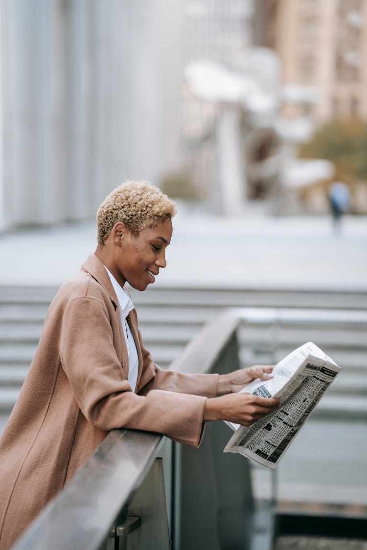 Smiling Businesswoman With Newspaper Near Railing