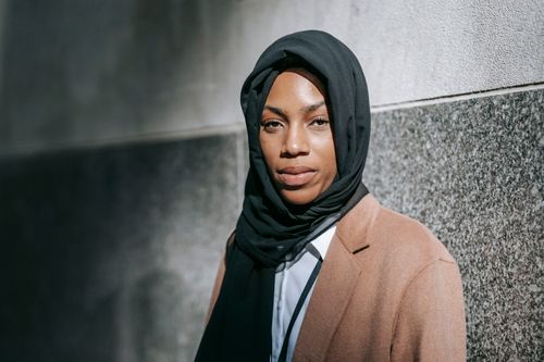 Free Serious African American female in black hijab and elegant brown coat looking at camera Stock Photo