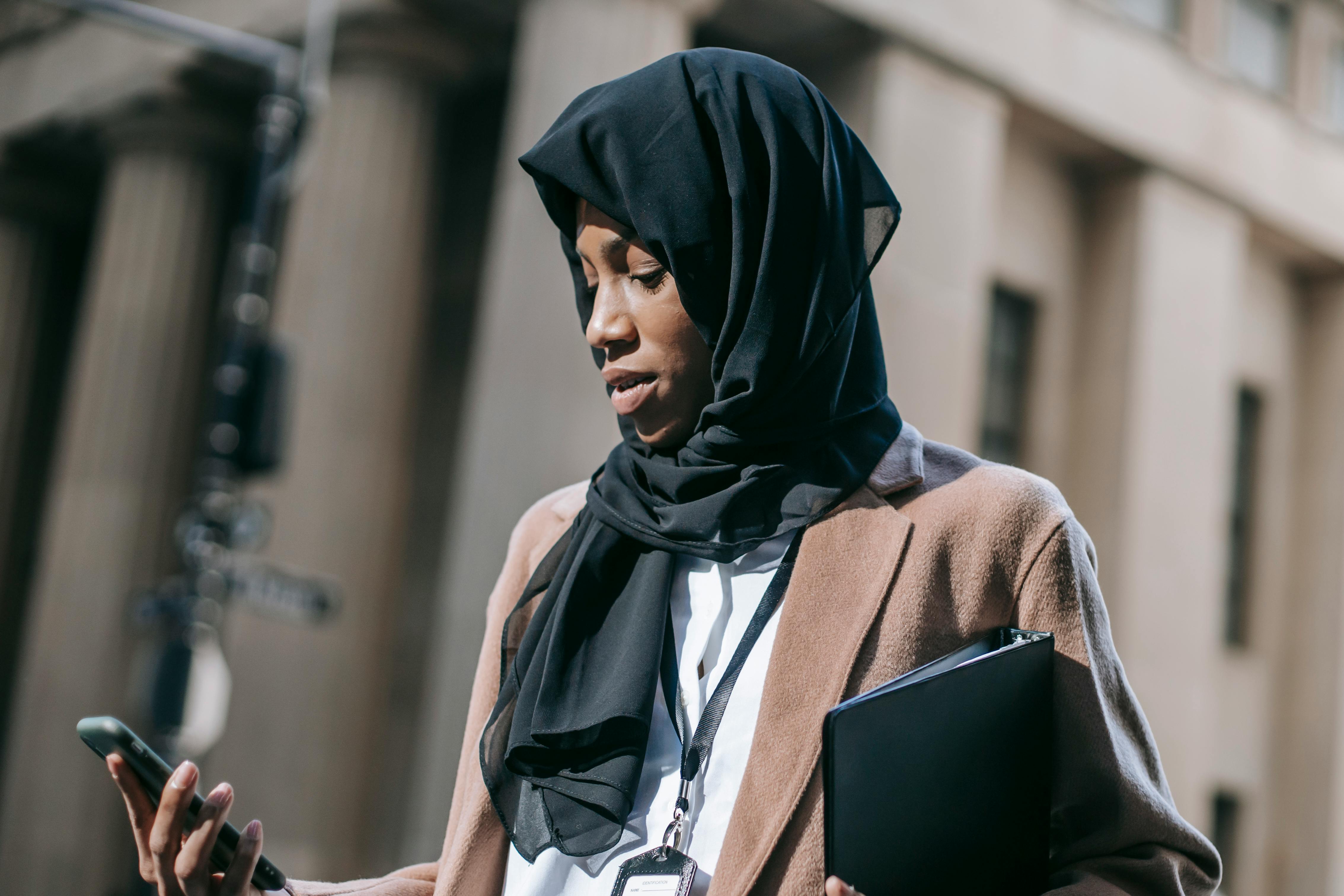 concentrated woman in headscarf text messaging