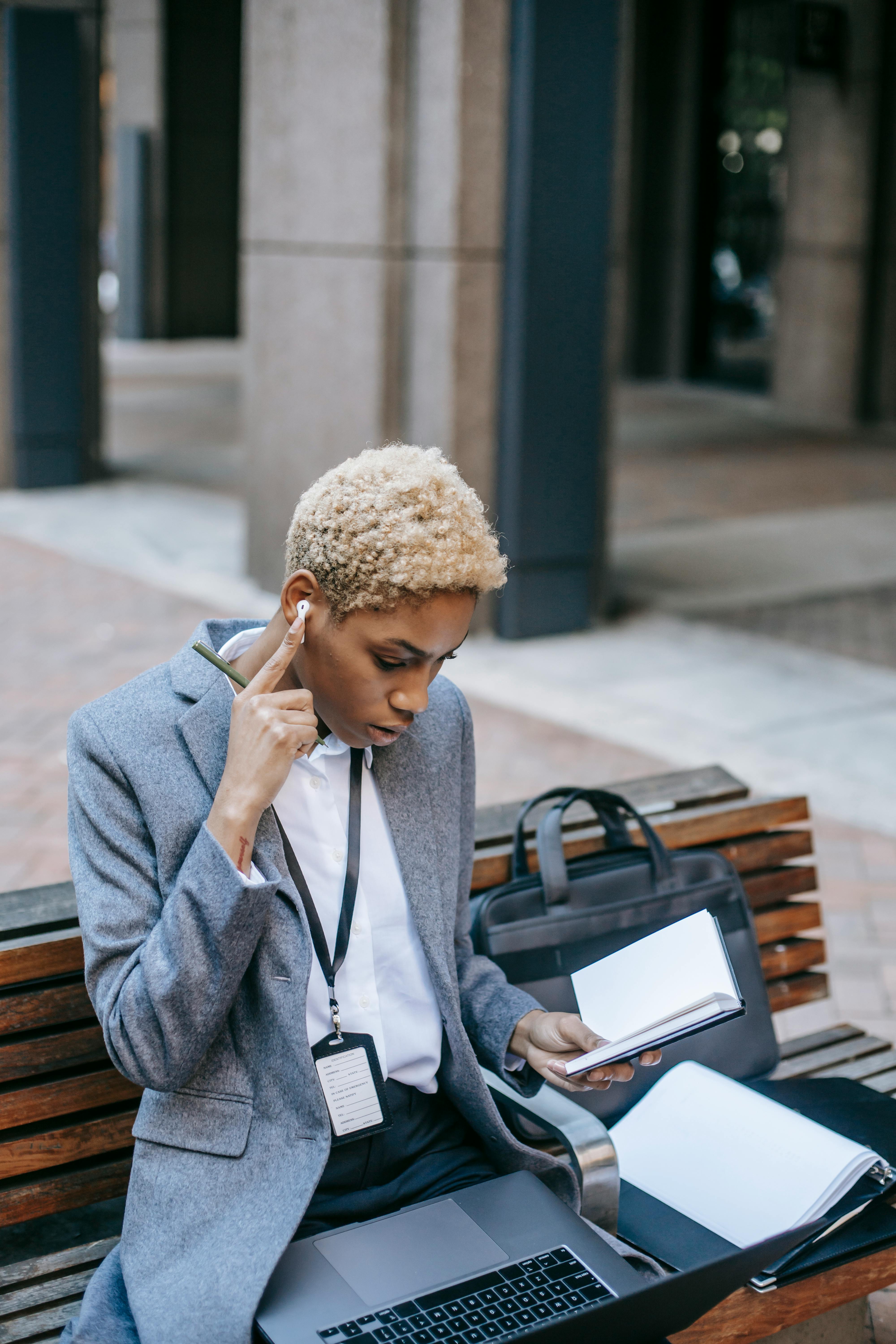 serious african american freelancer working while sitting on bench in city center