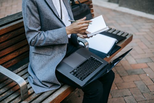 Free Crop black businesswoman writing information in planner while working outside Stock Photo