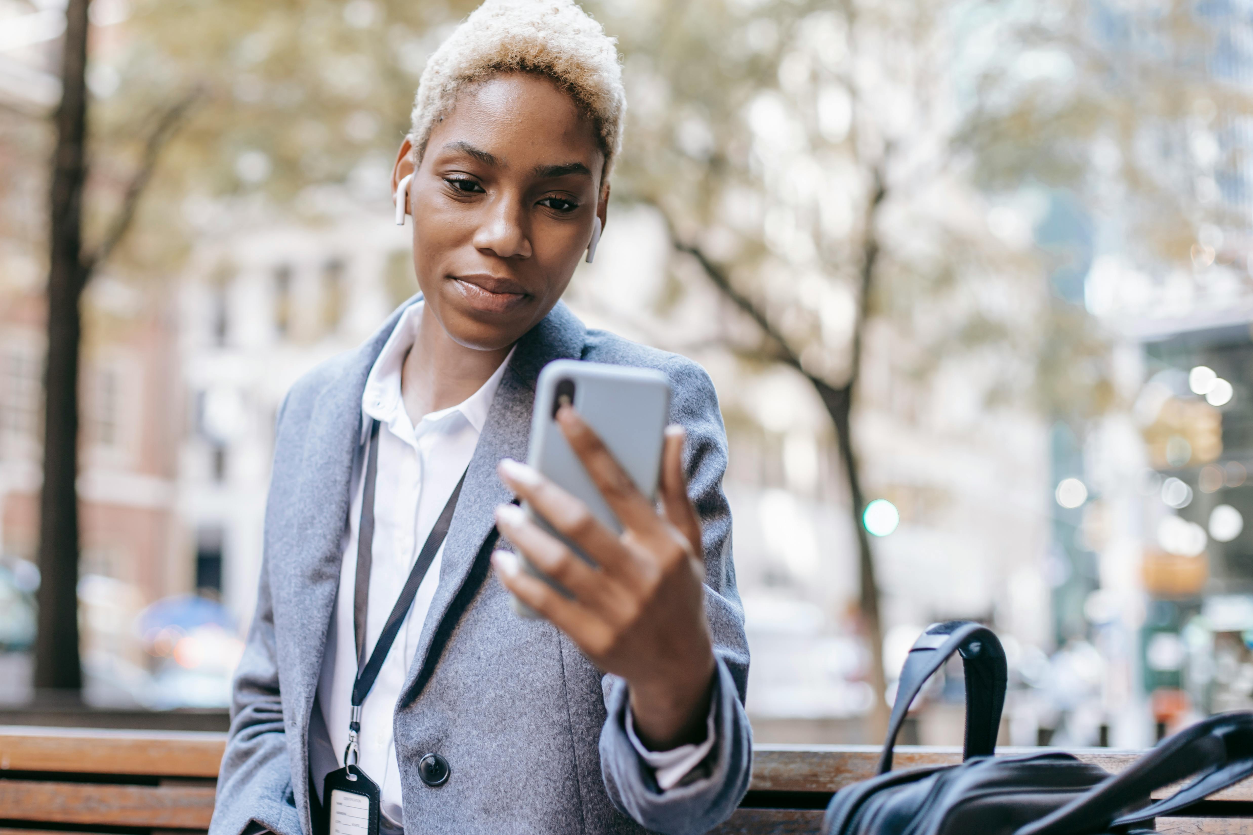 positive black woman reading text message on smartphone