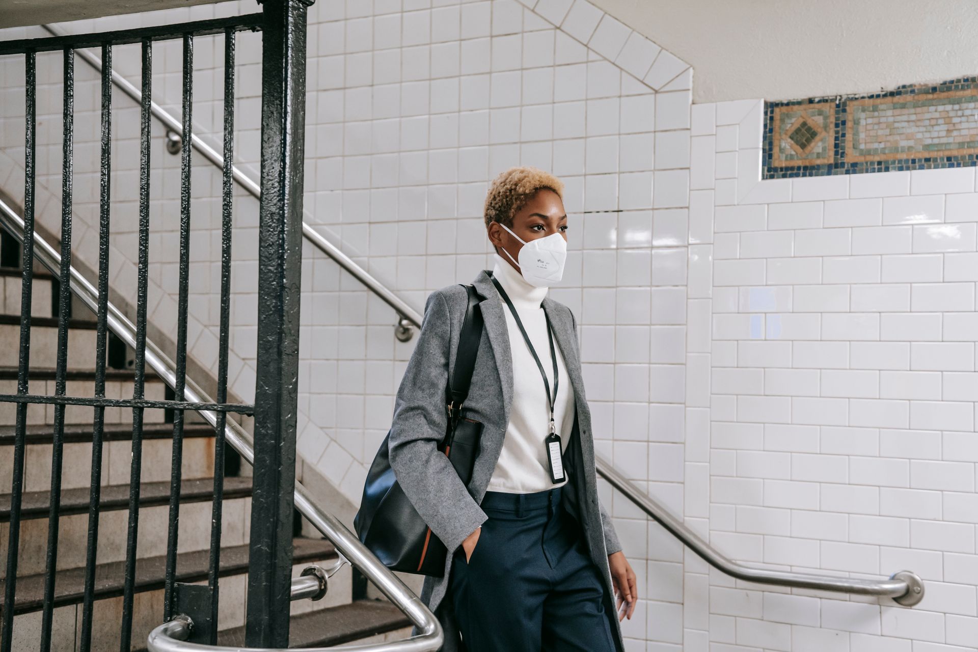 Confident businesswoman in mask commuting through urban subway station during pandemic.
