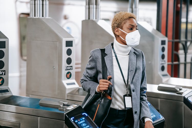 Young Black Woman In Mask Passing Turnstile In Metro