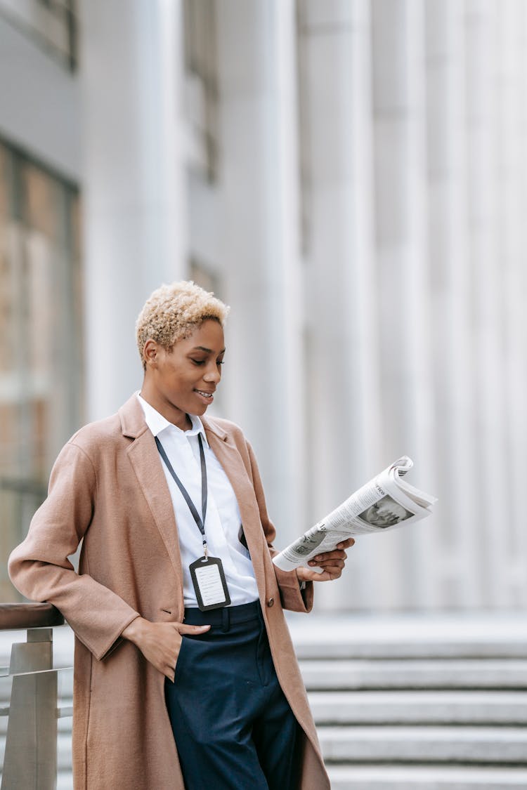 Smiling Black Businesswoman Reading Newspaper Outside Modern Building