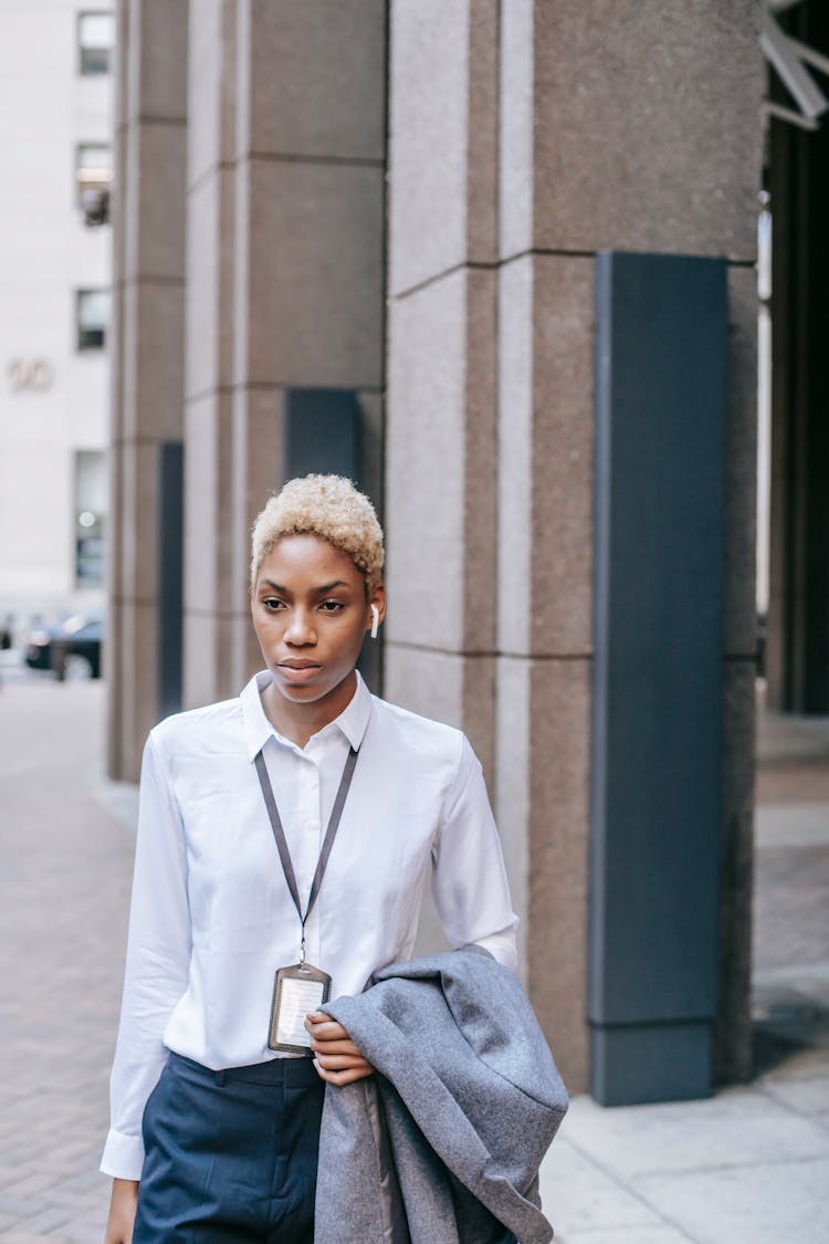 Black Woman Carrying Jacket On Hand And Walking On Street