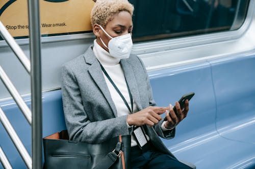 Crop black focused woman using smartphone in metro train
