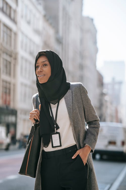 Stylish Muslim black woman standing on roadside in modern city