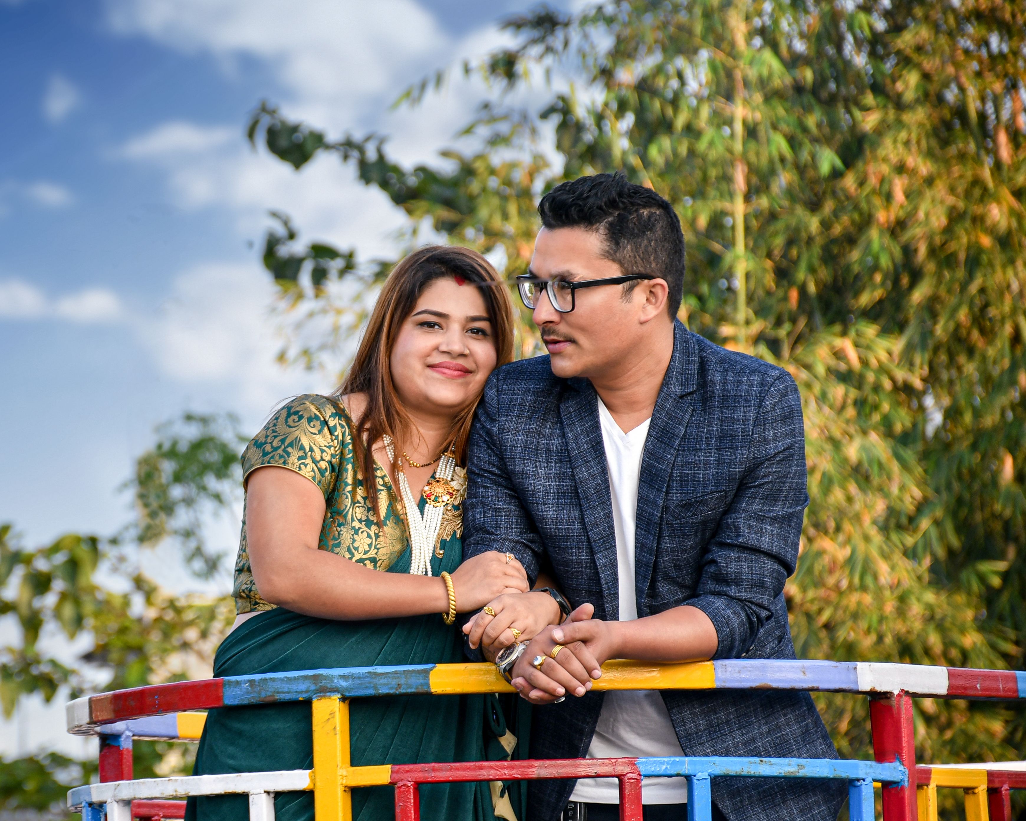 A loving couple enjoys a sunny day in Itahari, Nepal, captured in a vibrant outdoor setting.