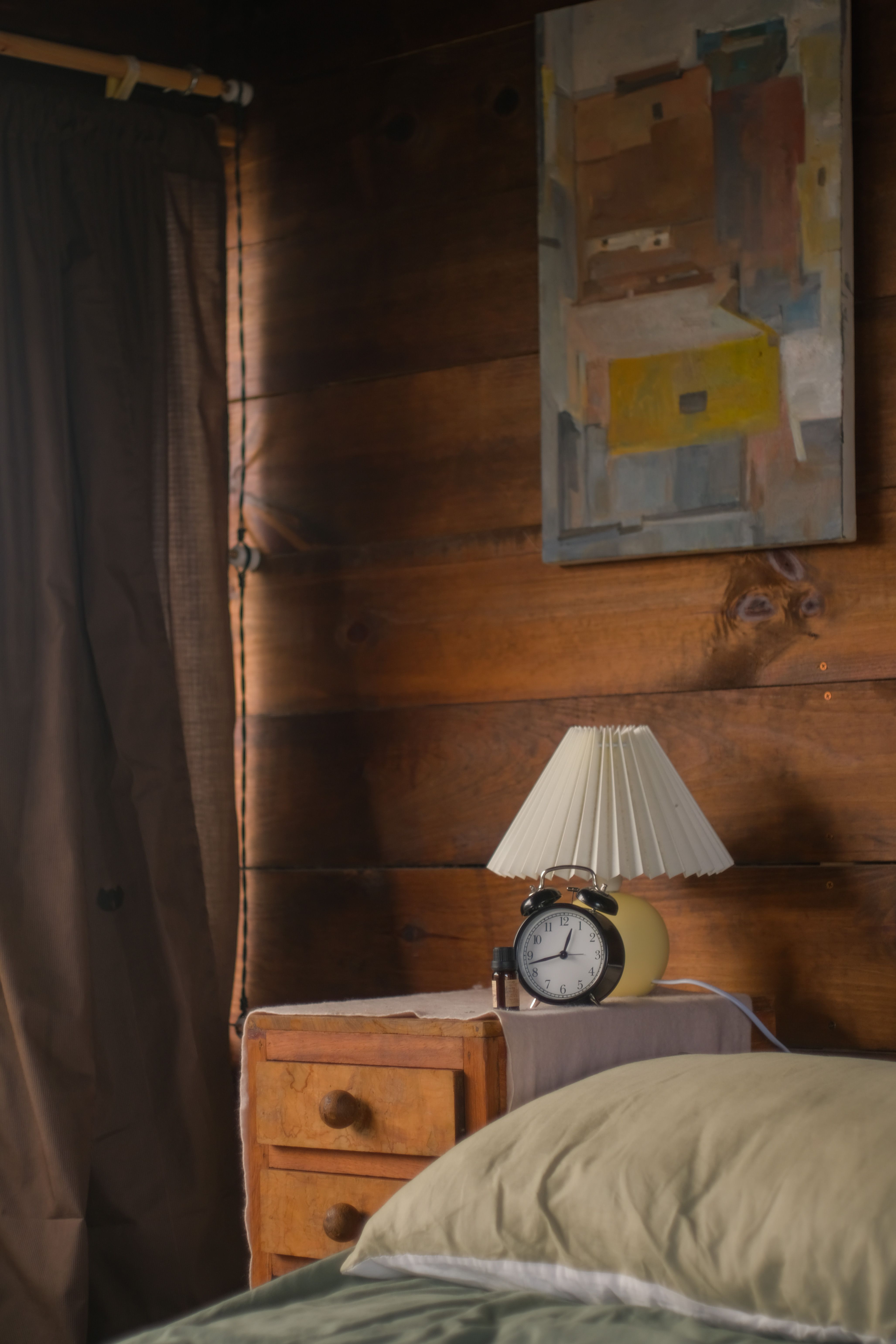 Relaxing rustic bedroom interior featuring a classic alarm clock on a wooden nightstand.