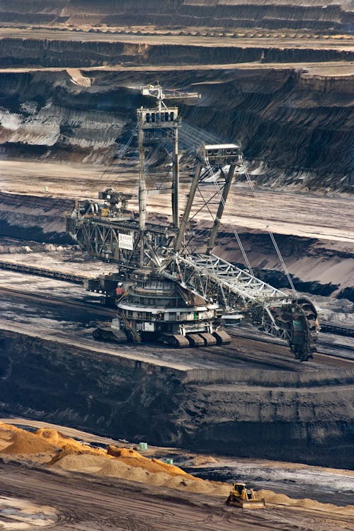 Silver Steel Mining Crane on Black Rocky Soil during Daytime