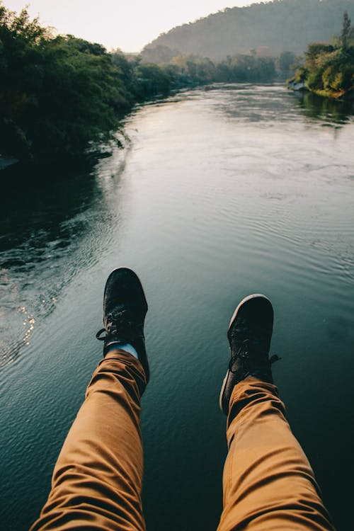 Free Man in Black Sneakers And Brown Pants Sitting in Front of the River Stock Photo