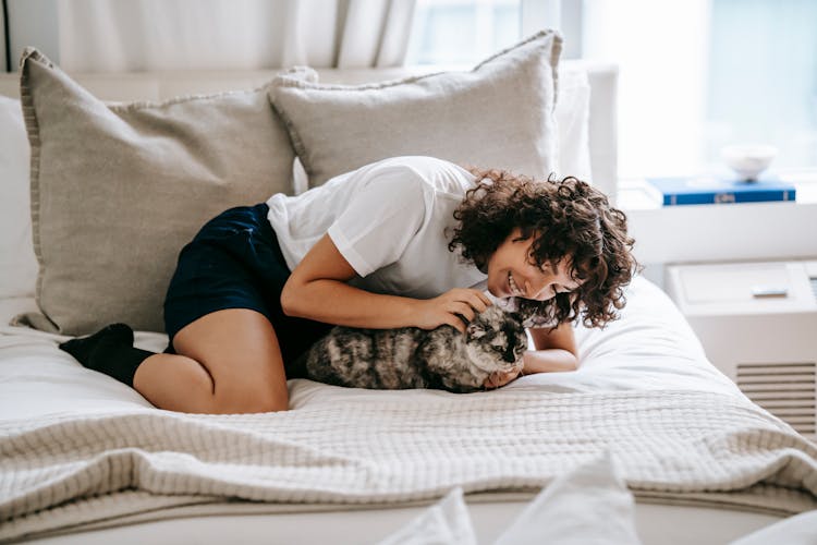 Happy Woman Playing With Lovely Cat On Cozy Bed