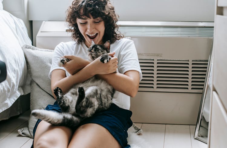 Cheerful Woman Playing With Cat