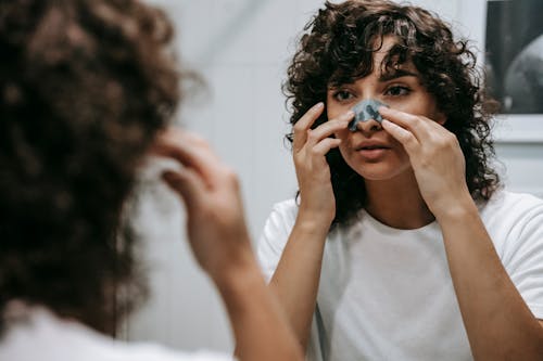 Calm woman applying skincare product on face