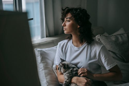 Dreamy woman with soft kitty at home