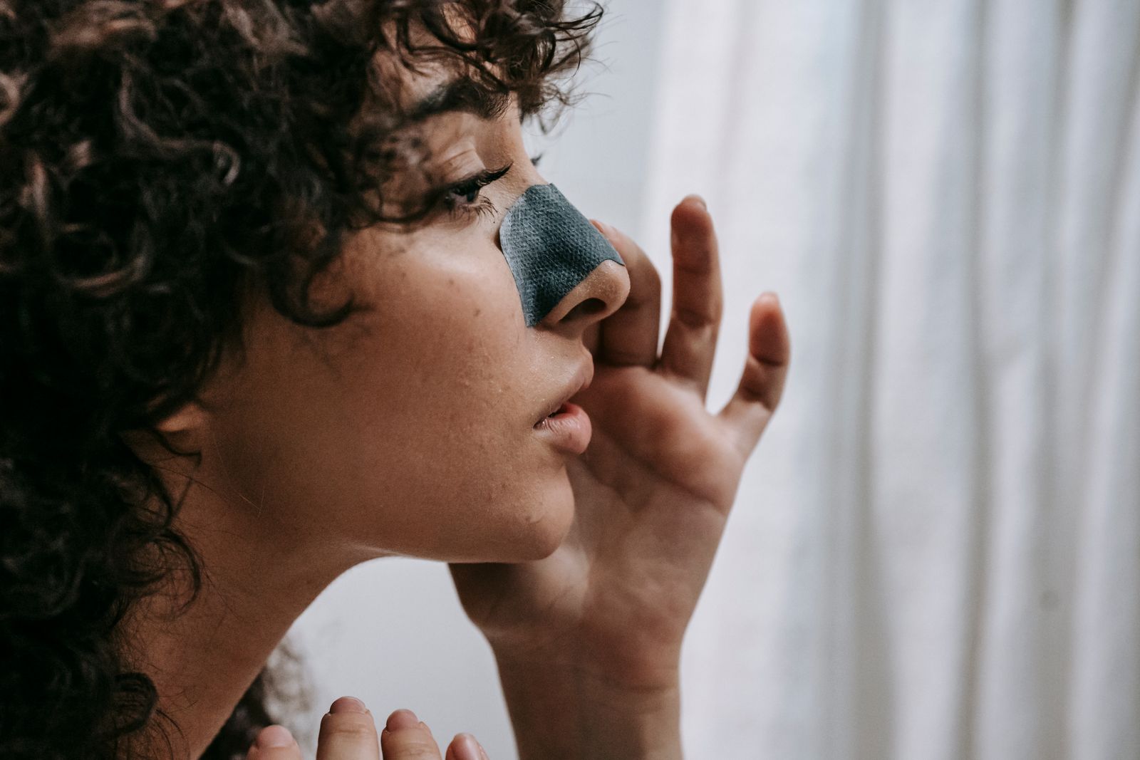 Woman using a personal facial care nose strip during an at-home routine