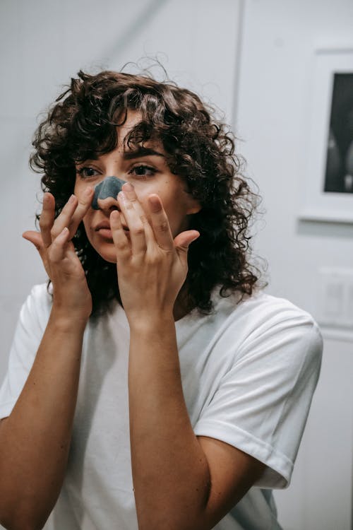 Young woman cleansing nose with cosmetic strip