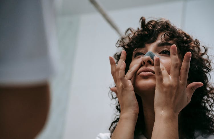 Female Applying Blackhead Removing Mask On Nose