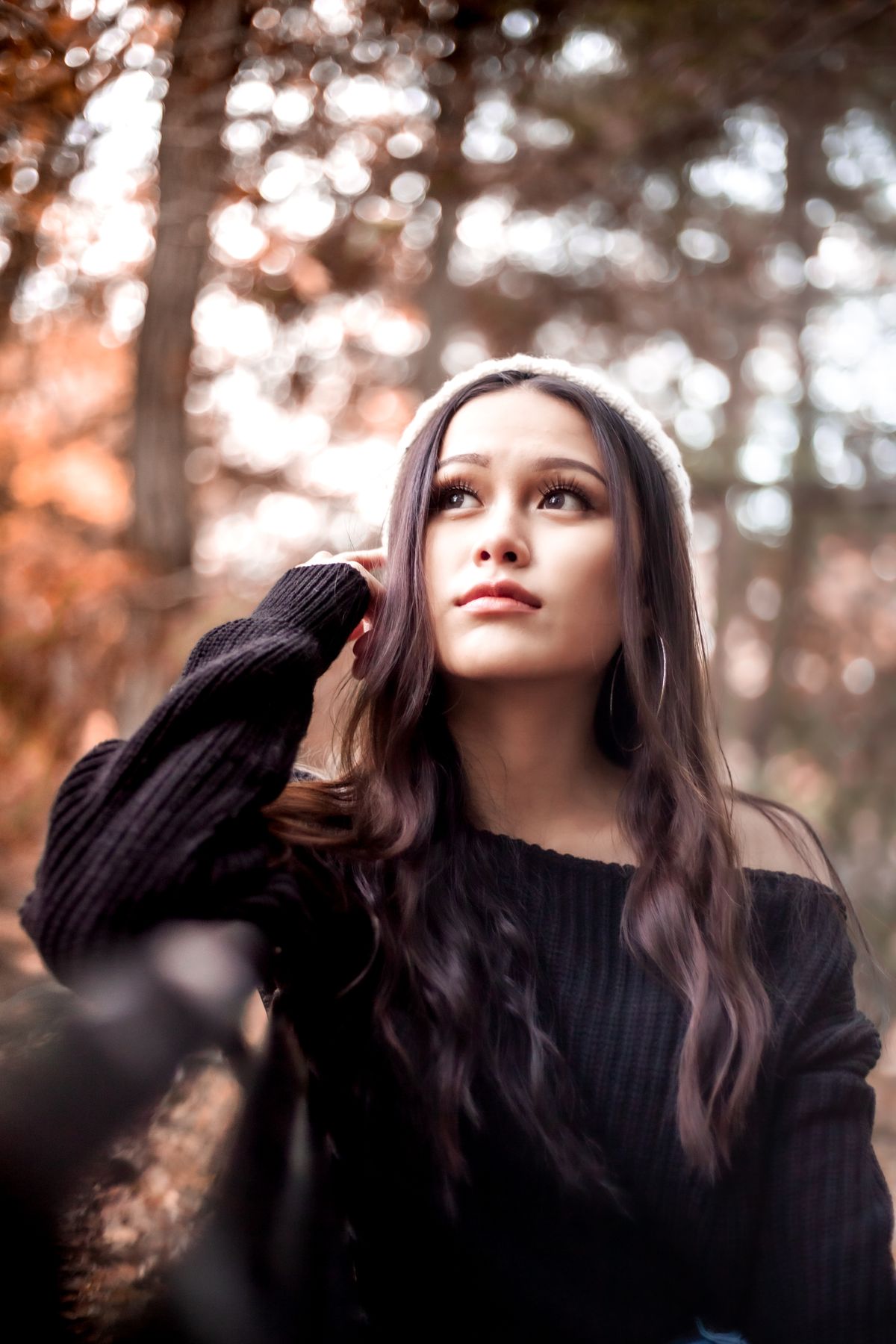 Woman in a knit sweater surrounded by autumn foliage