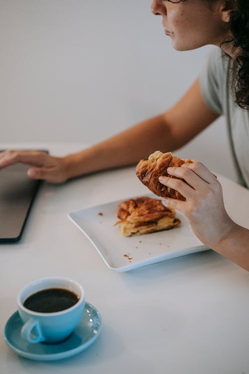 Free Crop woman using laptop during breakfast in kitchen Stock Photo