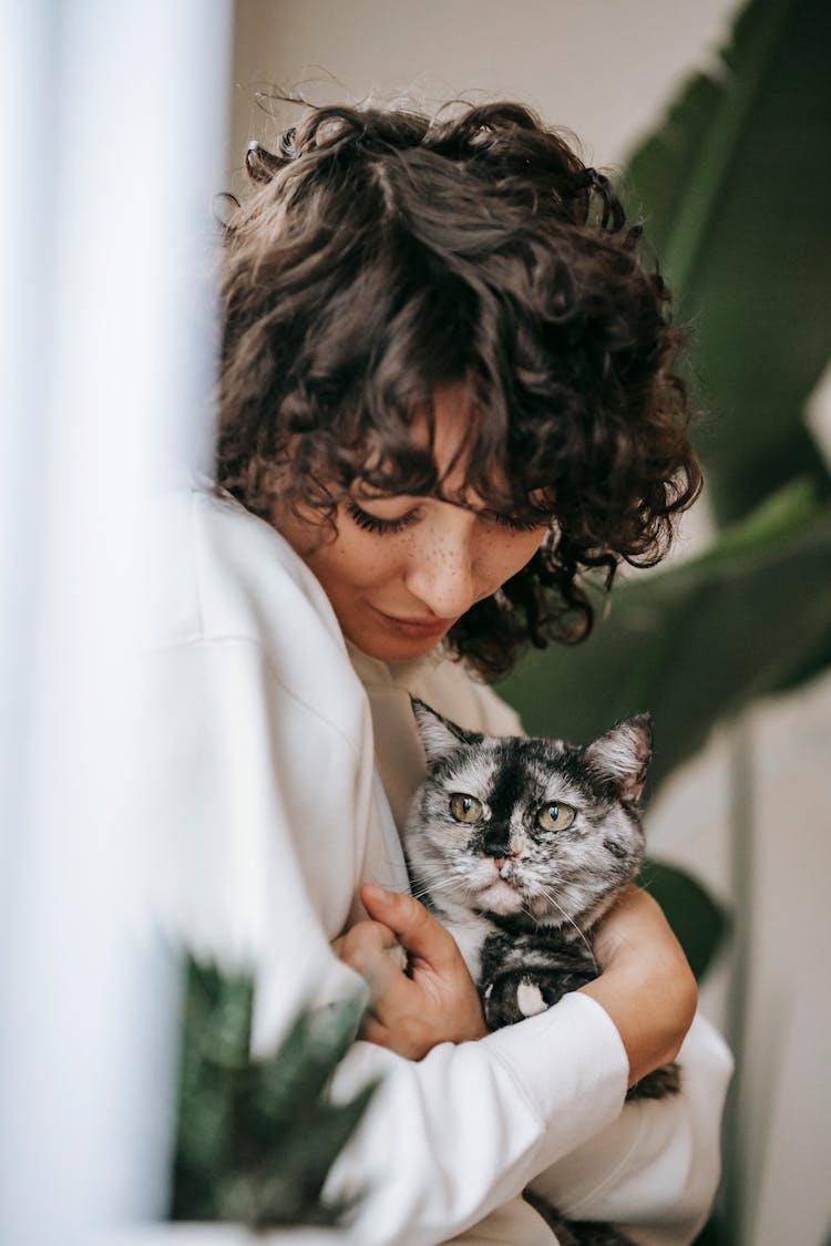 Woman Embracing Adorable Cat With Attentive Gaze At Home