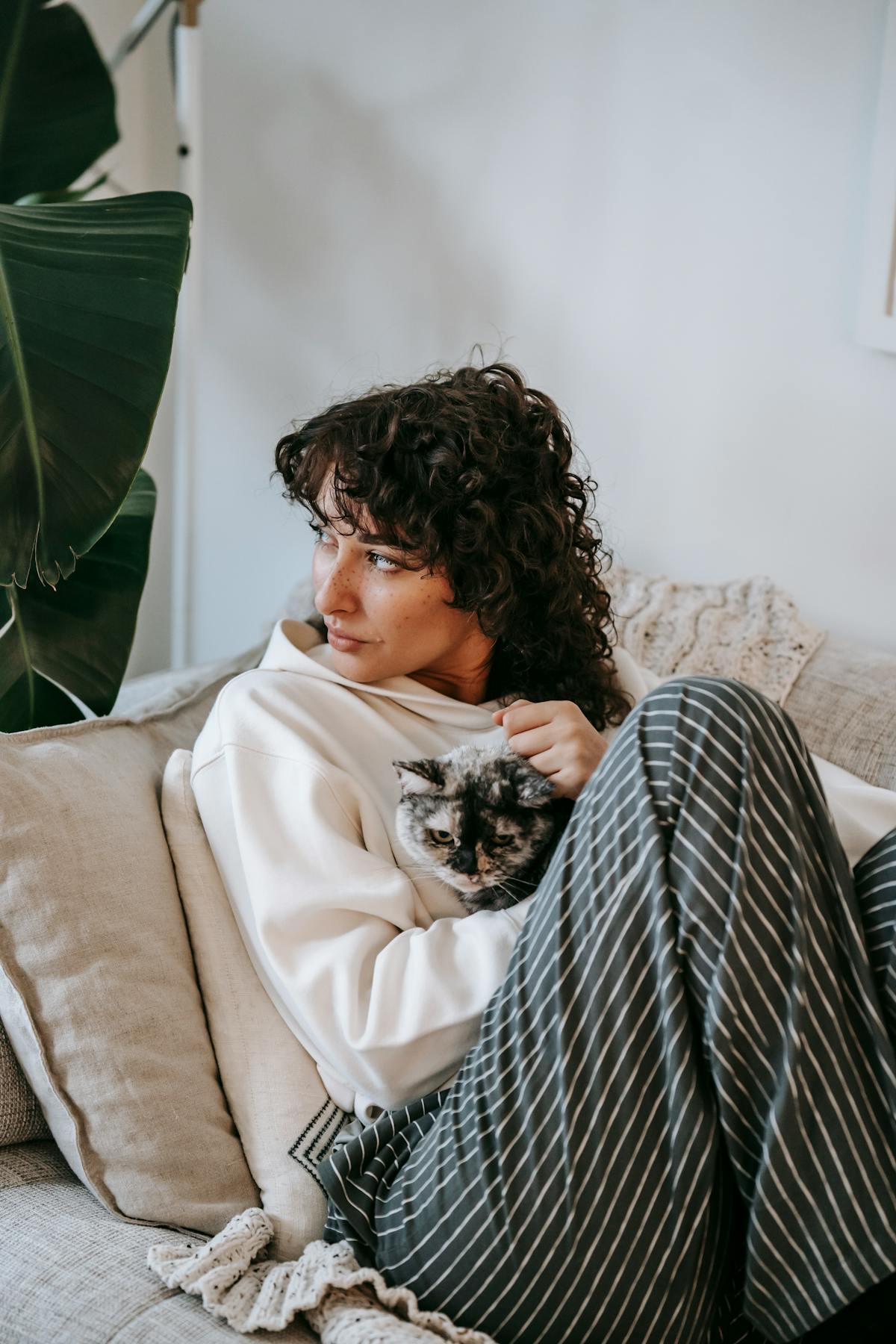 Donna adulta che si rilassa sul divano abbracciando un gatto