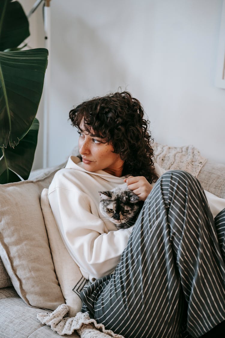 Dreamy Woman With Cat Resting On Sofa At Home