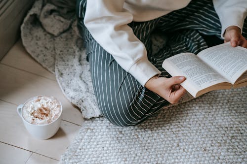 Female reading book while drinking coffee with whipped cream