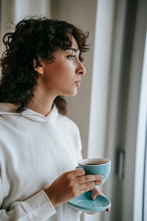 Free Thoughtful woman drinking hot coffee at home Stock Photo