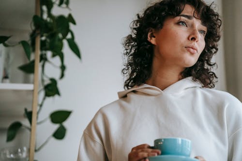 Free Pensive woman with hot beverage at home Stock Photo