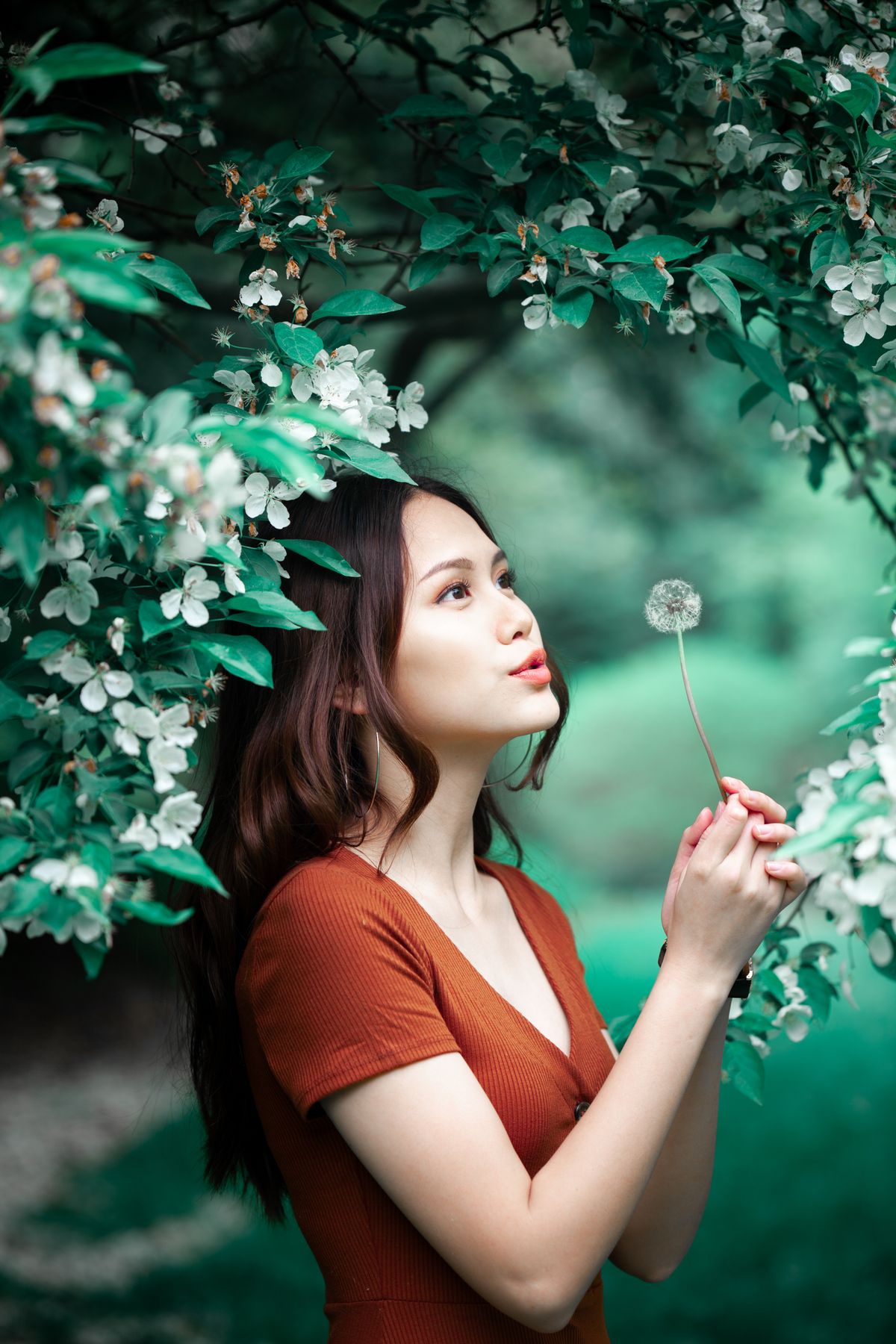 Young woman blowing a dandelion in a summer garden