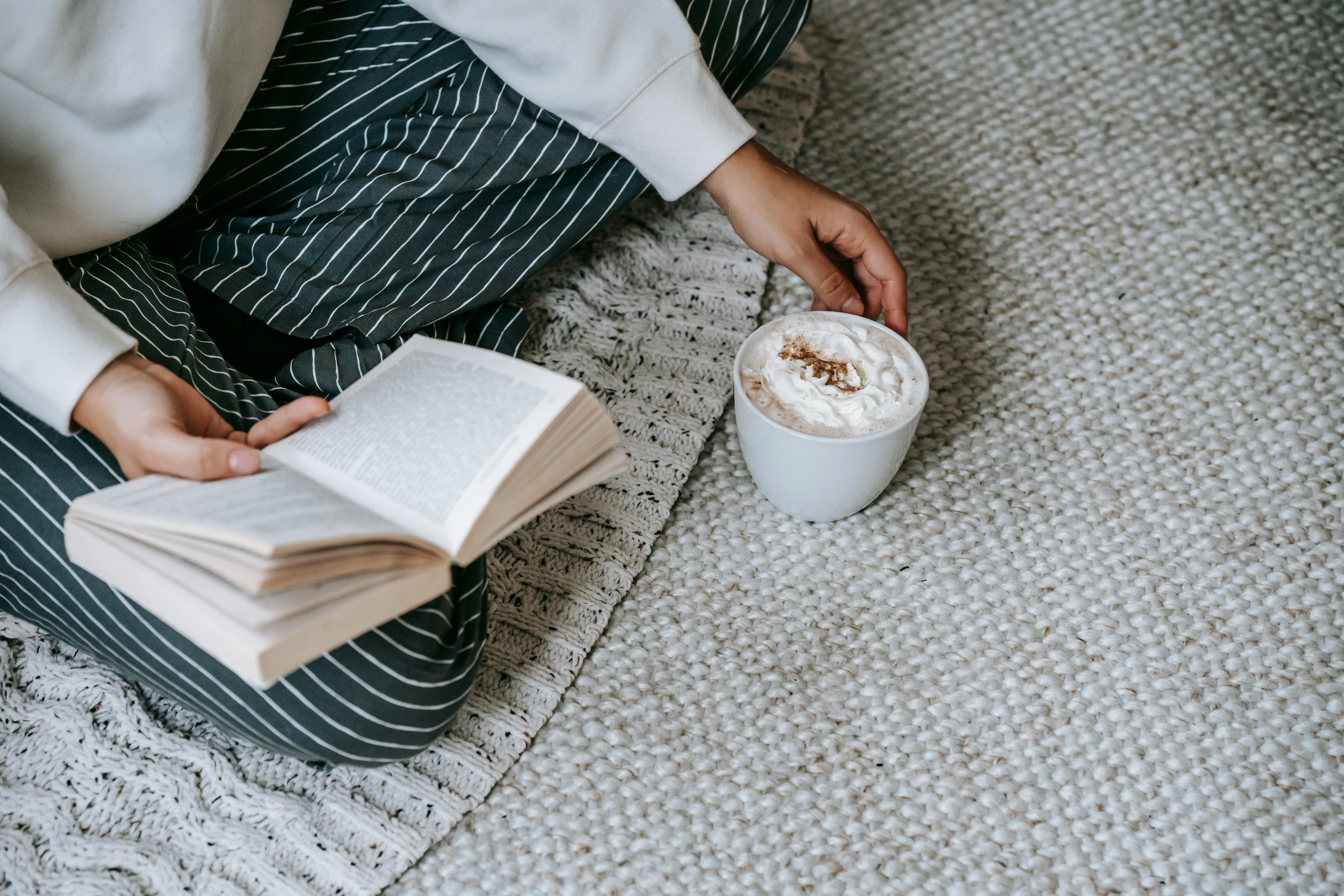 woman reading book with hot drink at home