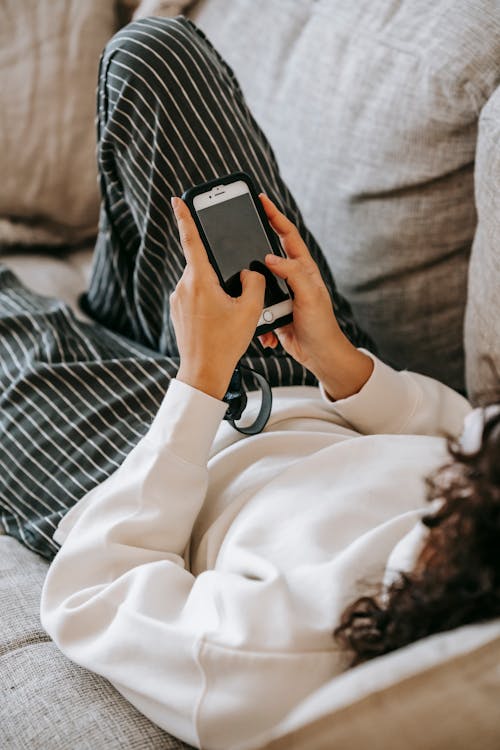 Woman using smartphone while resting on sofa