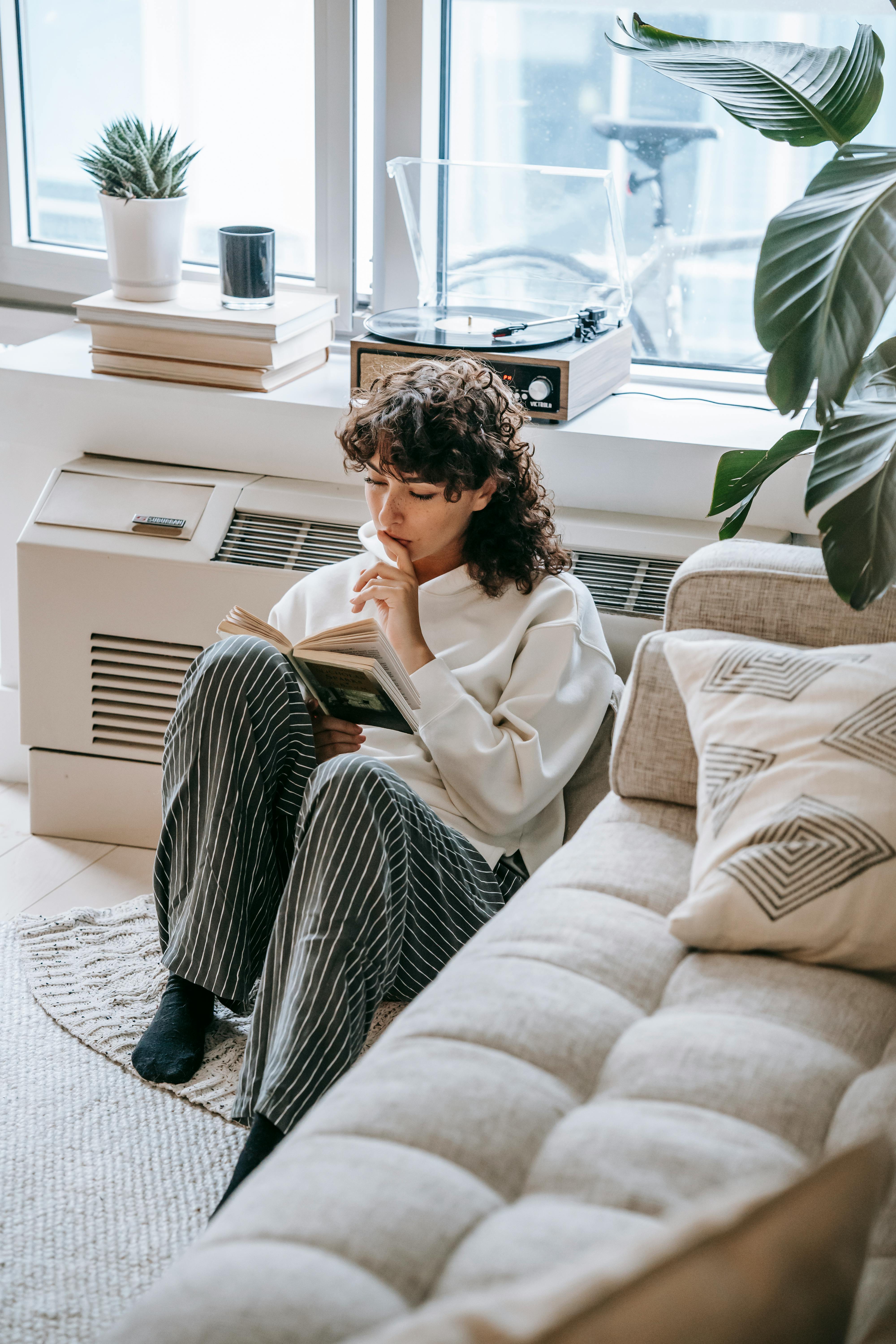 pensive woman reading book on floor in living room