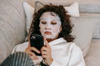 Woman in hydrating sheet mask browsing smartphone