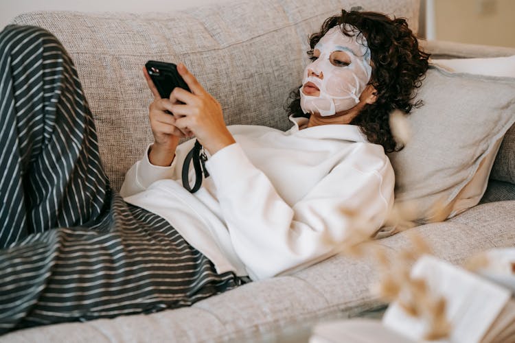 Focused Woman With Cosmetic Mask Browsing Phone