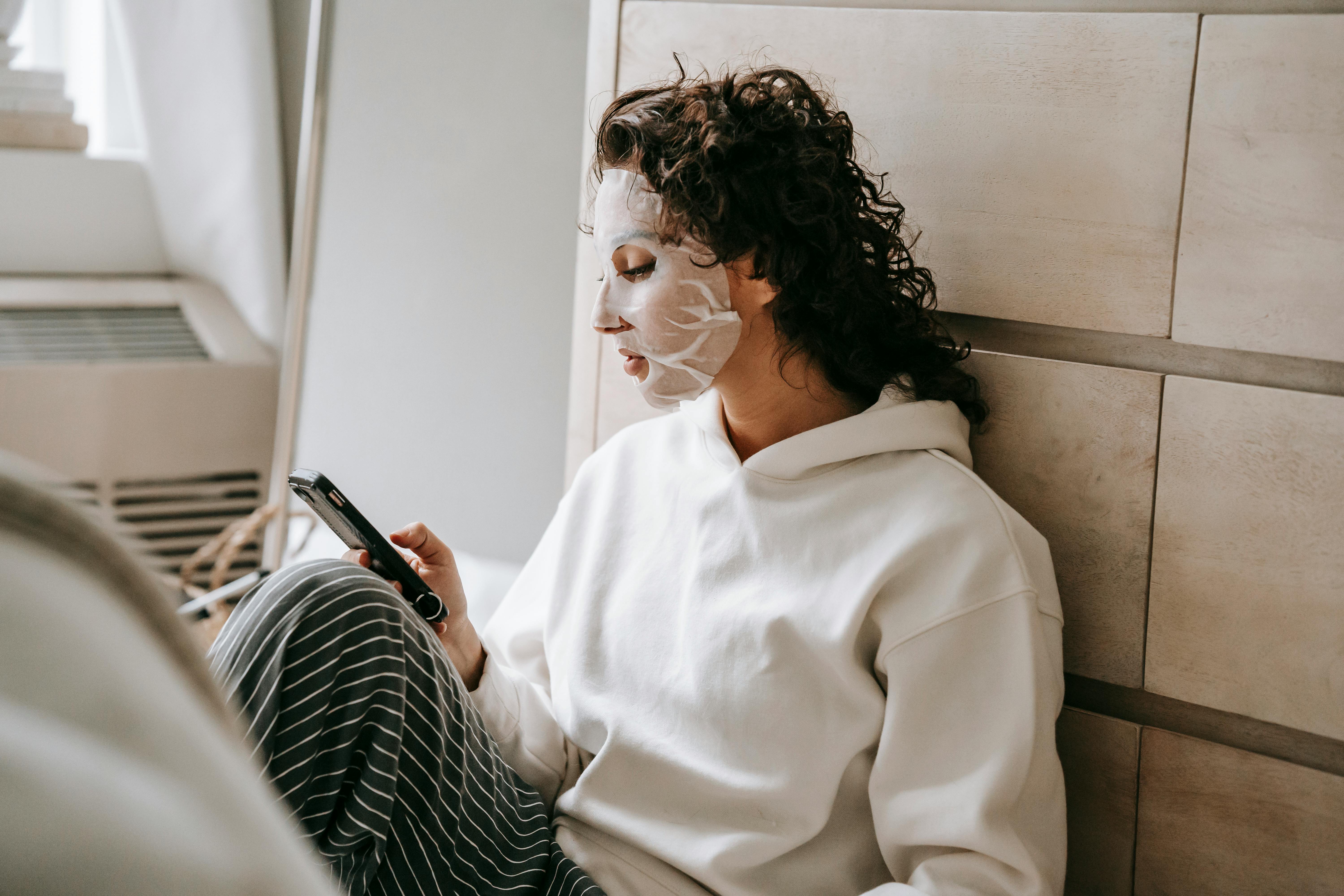 calm woman in mask texting on smartphone