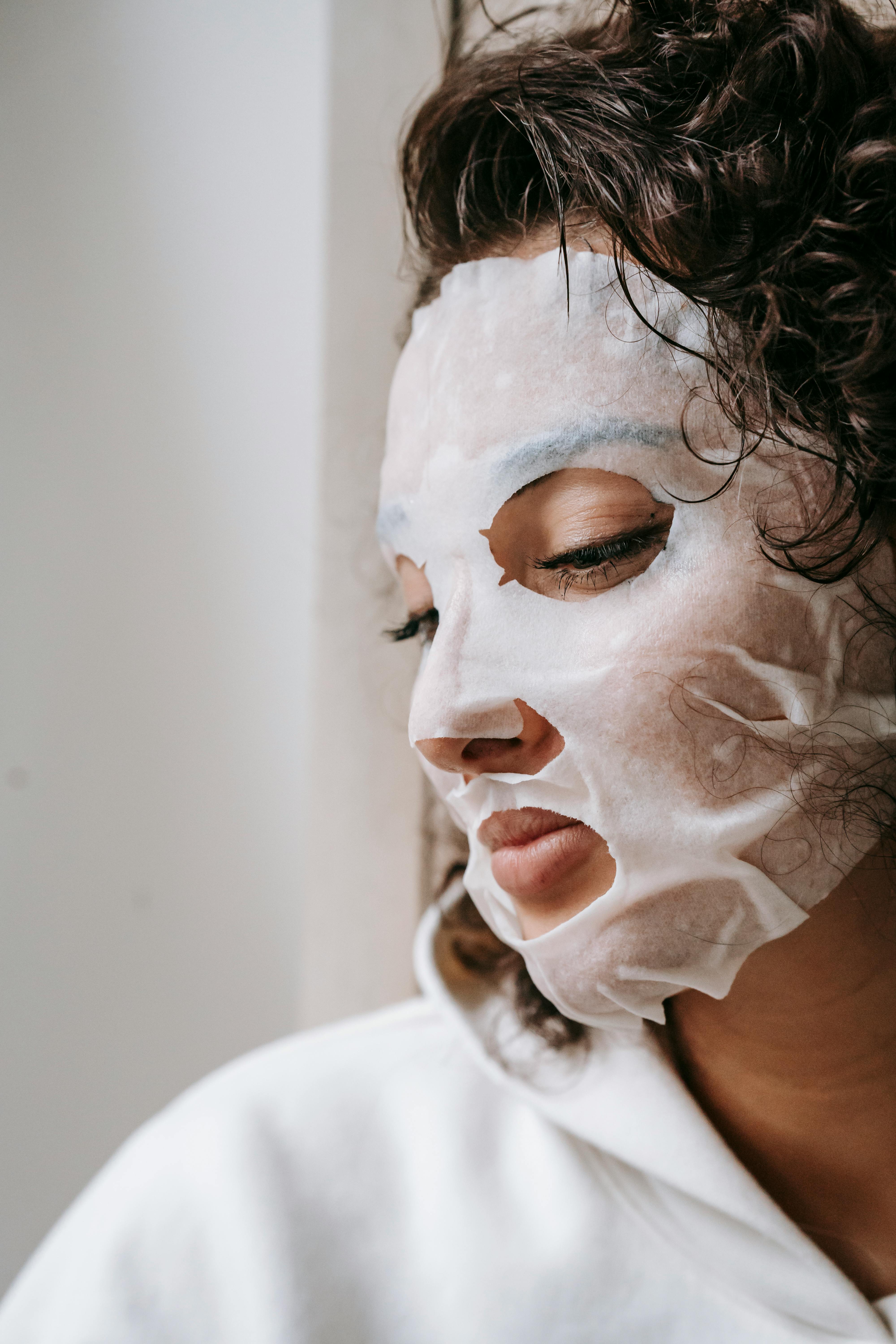 focused woman in sheet mask at home