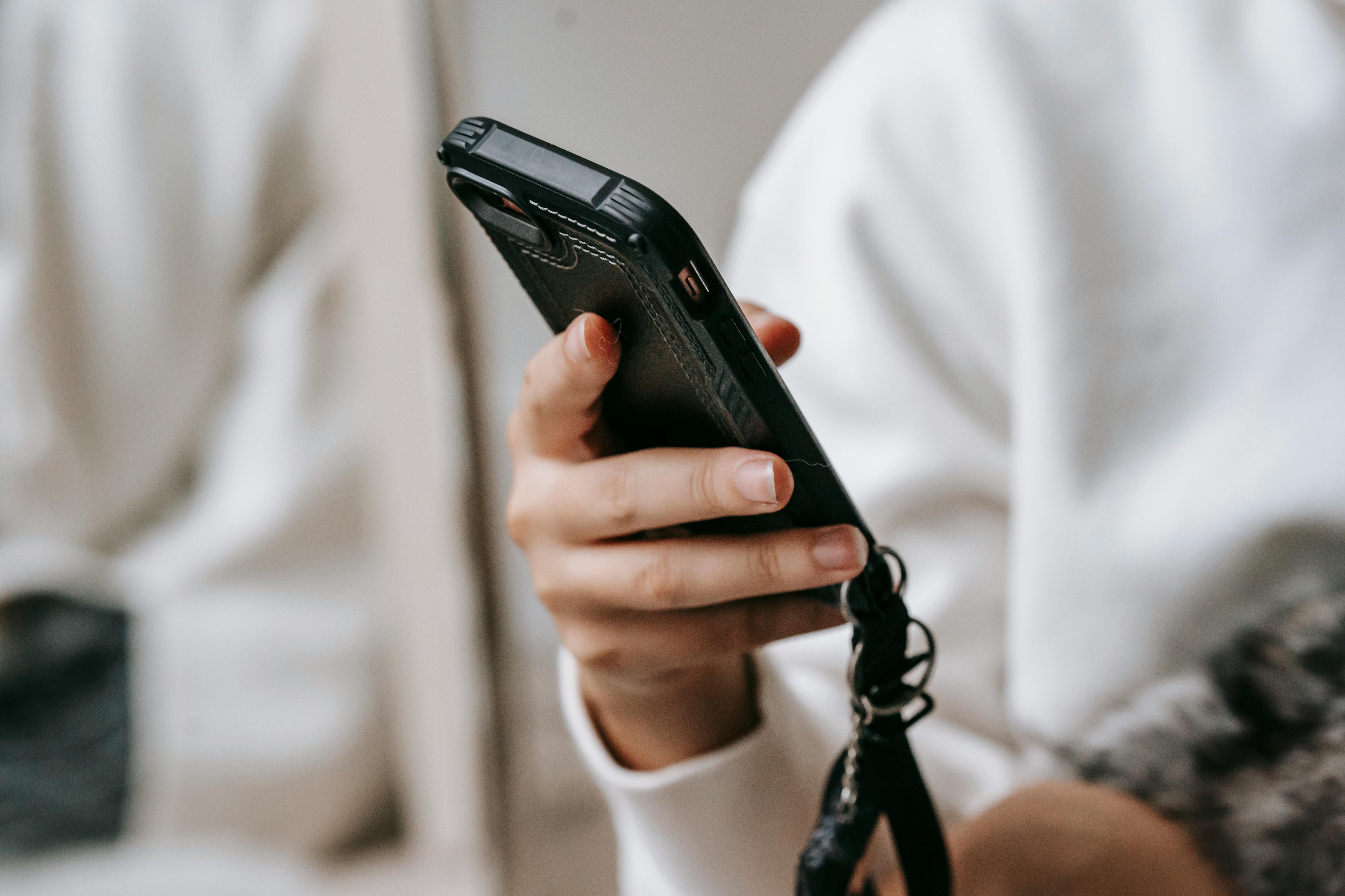 crop woman browsing smartphone in room