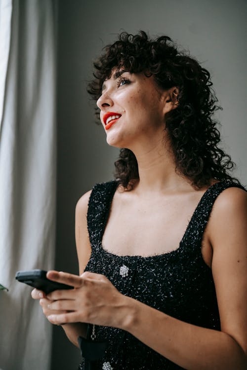 Smiling woman with smartphone at home in daytime