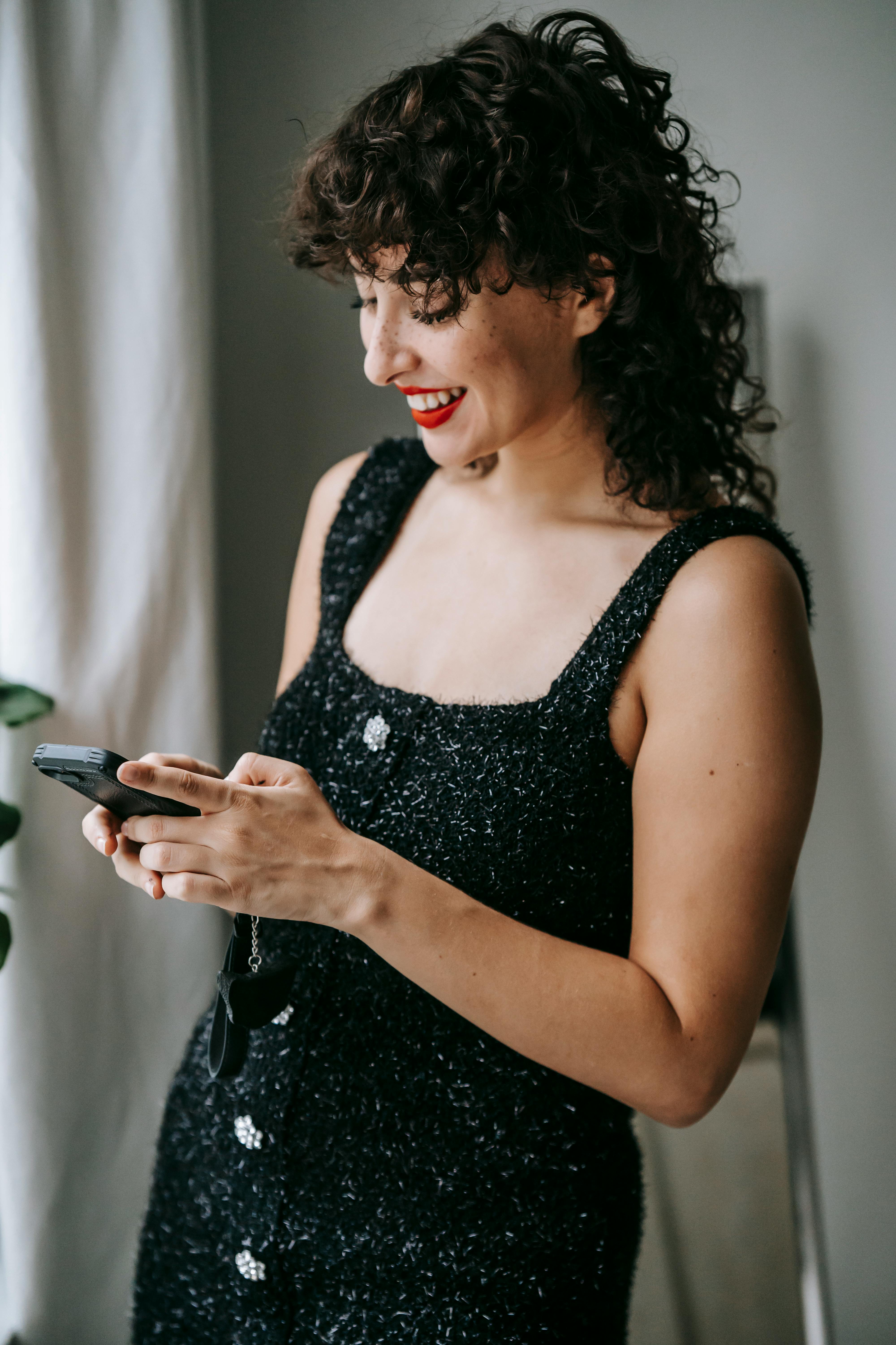 cheerful woman text messaging on smartphone in house