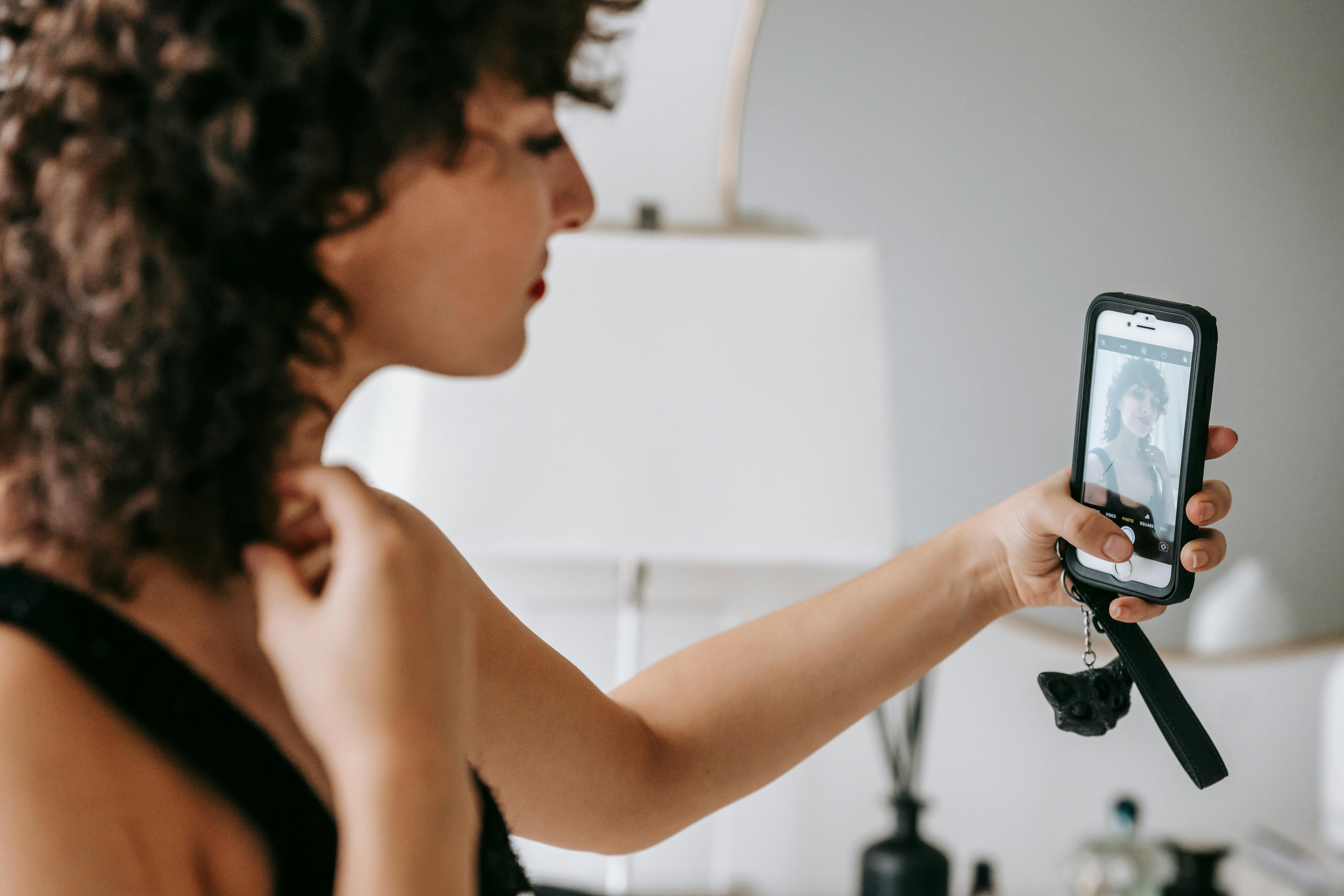 crop elegant woman taking selfie on smartphone at home